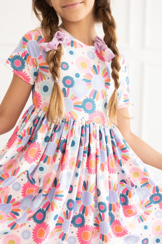 Young girl wearing a colorful floral dress with a white background