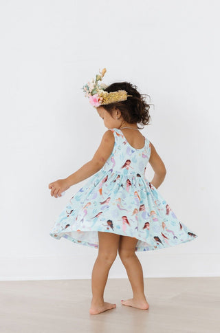 Child wearing a dress with mermaid pattern and floral headband on a white background