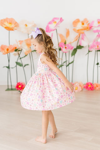 Young girl in a floral dress standing in front of flowers