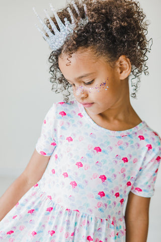 Young girl wearing a mermaid print dress with a white background