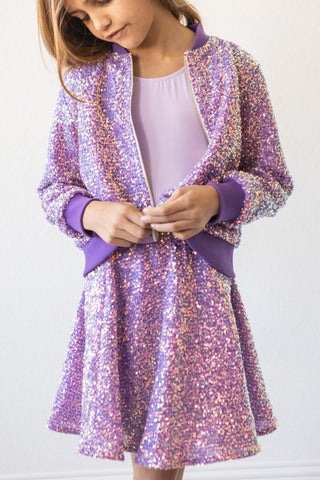 Child wearing a sparkling purple dress with a white background
