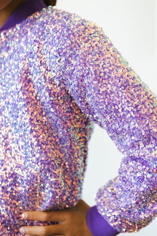 Close-up of a person wearing a sparkling, sequined garment with a blurred background.