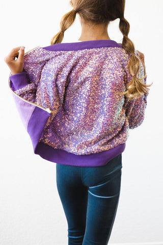 Person wearing a purple sequin jacket and blue leggings on a white background