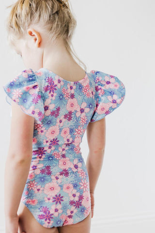 Child wearing a floral leotard with ruffled sleeves on a white background