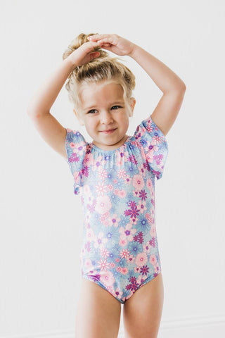 Young girl wearing a floral leotard on a white background