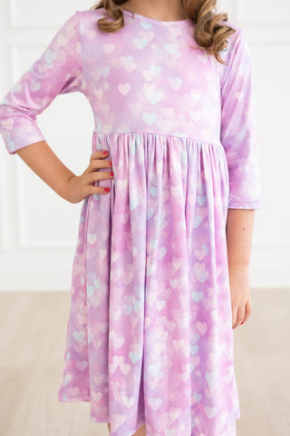 Pink dress with heart pattern worn by a child against a white background