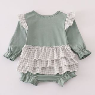 Green baby romper with ruffled layers on a light gray background