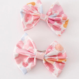 Two pink hair bows with floral patterns and character mouse prints, one with a lighter background and the other with a darker background.