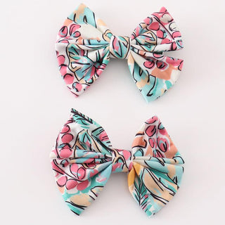 Two teal floral print hair bows on a white background