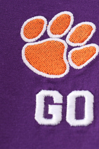 Close-up of orange tiger paw embroidery on purple boy top