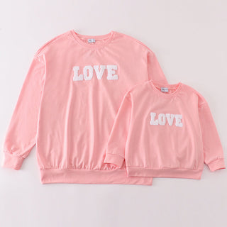 A pink French knot top for moms and children with the word 'love' written in large white letters.