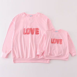 A pink long-sleeve French knot top with the word 'love' written in a heart shape, presented in two sizes, with a smaller version below the larger one.