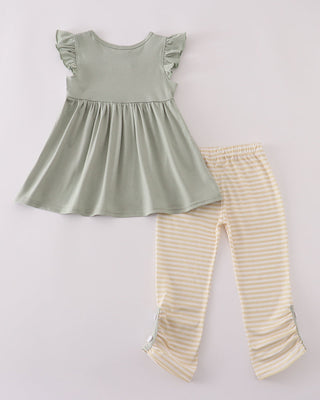 Green top and beige striped pants on a light gray background