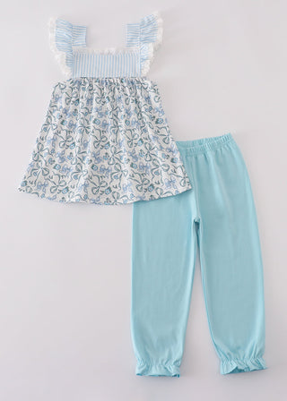 Children's outfit with floral top and light blue pants on a white background