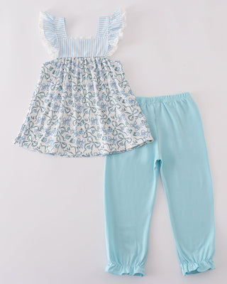 Children's outfit with floral top and light blue pants on a white background