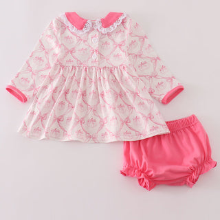 Baby dress and bloomers set with pink and white pattern on a light gray background