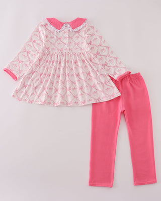Children's outfit with a patterned top and pink pants on a light gray background