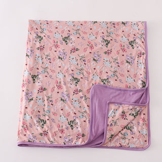 Floral-patterned blanket with a purple border on a light pink background