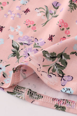 Floral fabric with pink background and green leaves on a white surface