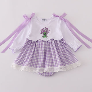 Baby outfit with white top and purple checkered skirt on a light gray background