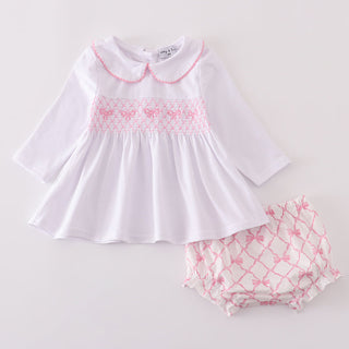 Baby white top with pink smocking and matching bloomers on a light gray background