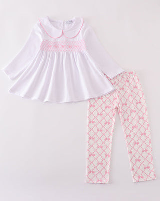 White top with pink smocking and matching pants on a white background
