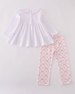 White top and pink patterned pants on a light gray background