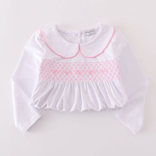White blouse with pink smocked collar on a light gray background