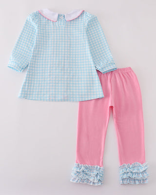 Children's outfit with checkered top and pink pants on a light gray background