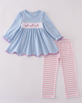 Children's outfit with blue top and pink striped pants on a light gray background