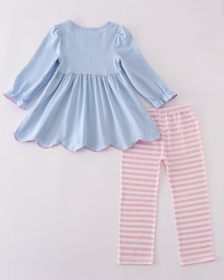 Light blue top and pink striped pants on a light gray background