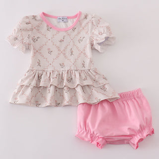 Baby outfit with floral top and pink bloomers on a light gray background