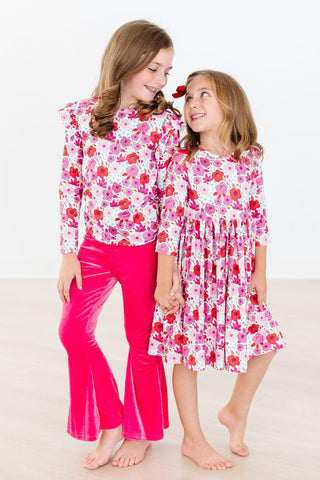 Two young girls wearing floral outfits on a white background