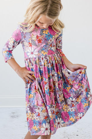 Young girl wearing a colorful floral dress against a white background