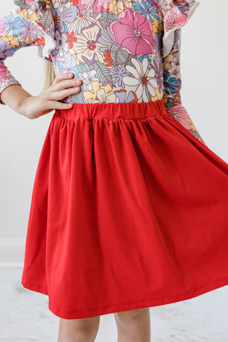 Person wearing a colorful floral leotard and red skirt on a white background