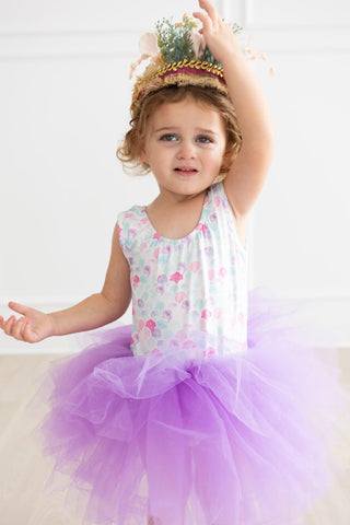 Child in a leotard and purple tutu with a crown on a white background