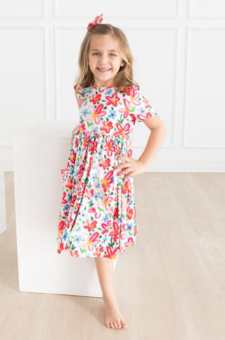 Young girl wearing a colorful floral dress against a white background