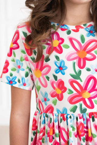 Child wearing a colorful floral dress with a plain background