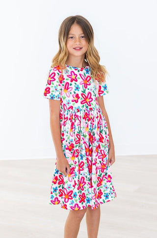 Young girl wearing a colorful floral dress on a white background