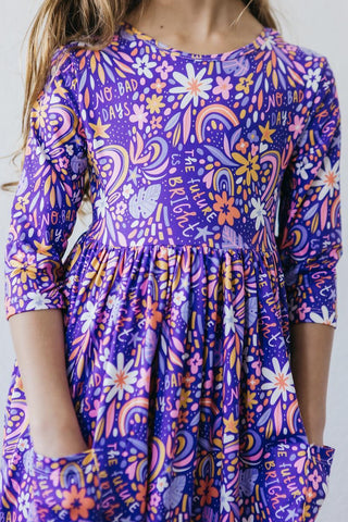 Child wearing a colorful dress with floral and abstract patterns on a white background