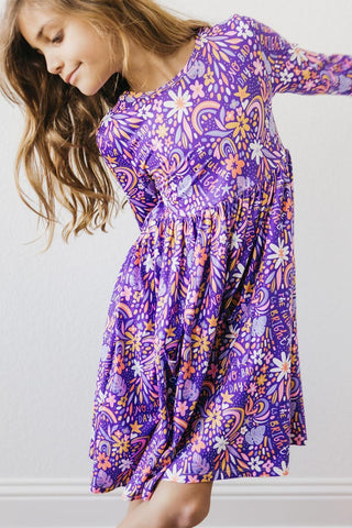 Young girl wearing a purple floral dress against a plain background