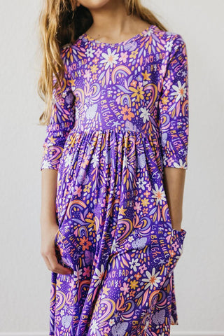 Child wearing a purple floral dress on a plain background