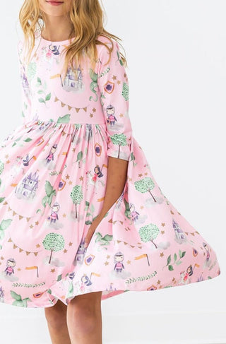 Pink dress with princess theme print on a white background