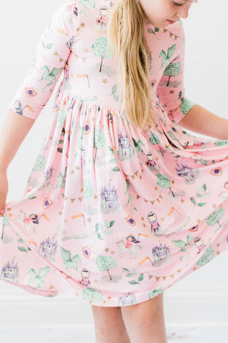 Child wearing a pink dress with a princess print on a white background