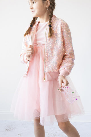 Young girl in a pink dress with a sequined jacket on a white background