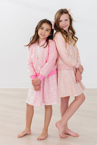 Two young girls wearing matching sequin sets on a white background