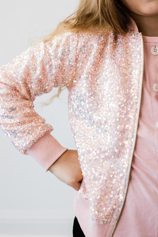 Close-up of a person wearing a peach sequin jacket on a light gray background