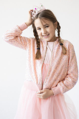 Young girl in a peach sequin outfit with a tiara on a white background