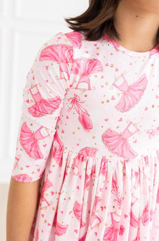 White dress with pink ballerina pattern worn by a young girl