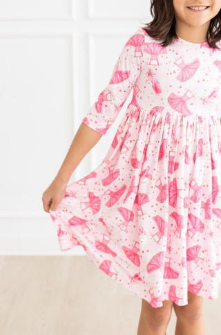 Child wearing a pink ballerina-patterned dress against a white background